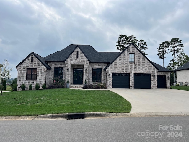 french country style house featuring a garage and a front lawn