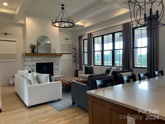 living room featuring beam ceiling, light hardwood / wood-style floors, coffered ceiling, and a stone fireplace