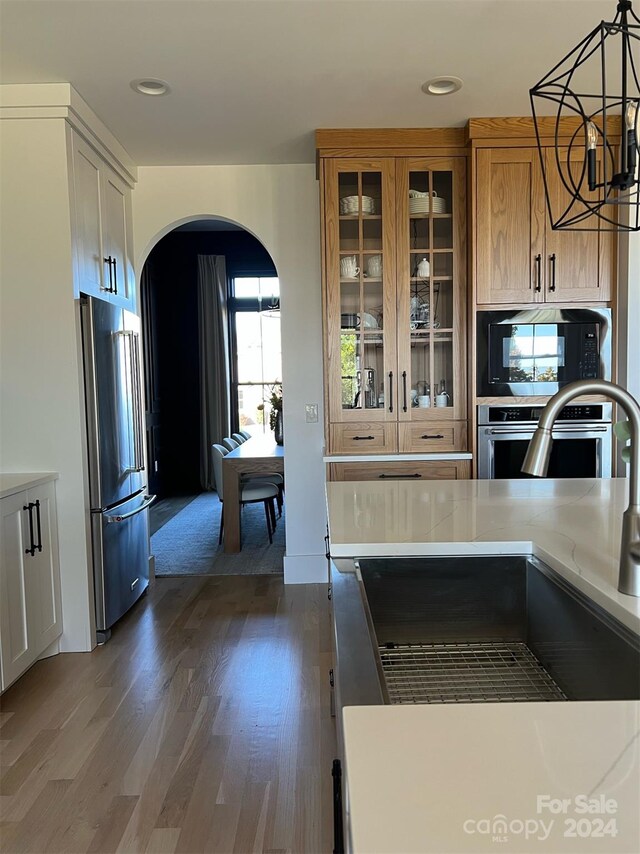 kitchen featuring pendant lighting, sink, appliances with stainless steel finishes, dark hardwood / wood-style floors, and a notable chandelier