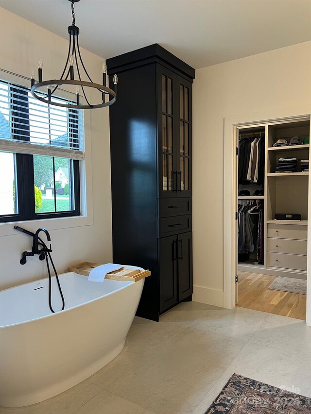 bathroom featuring wood-type flooring, an inviting chandelier, and a bathing tub