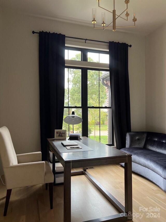 dining area with an inviting chandelier, wood-type flooring, and a healthy amount of sunlight