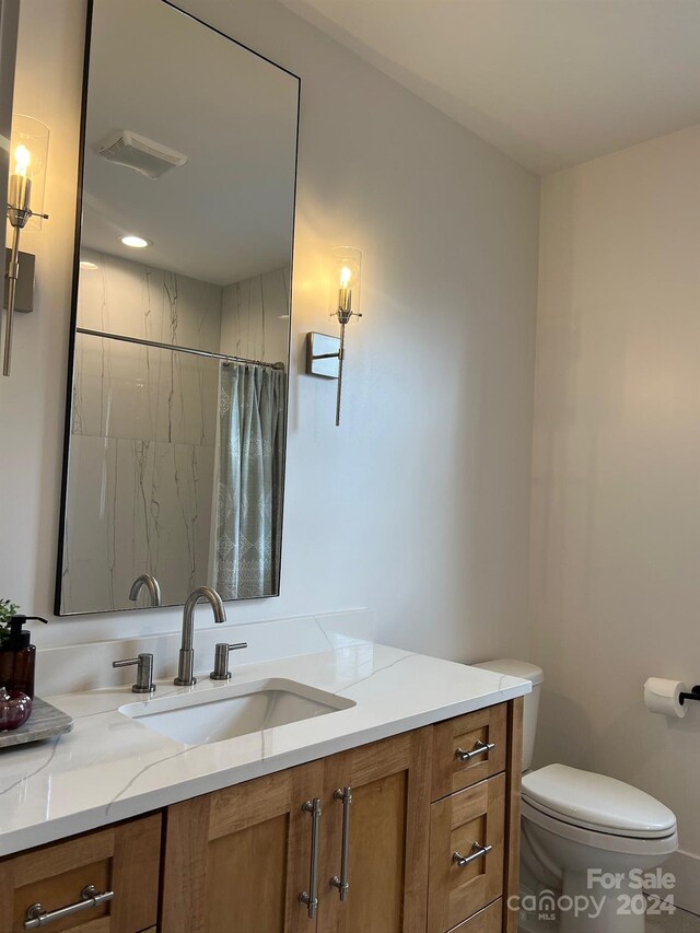 bathroom with curtained shower, vanity, and toilet