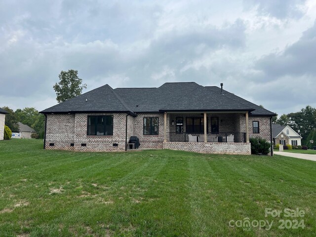 back of property with a yard and a porch