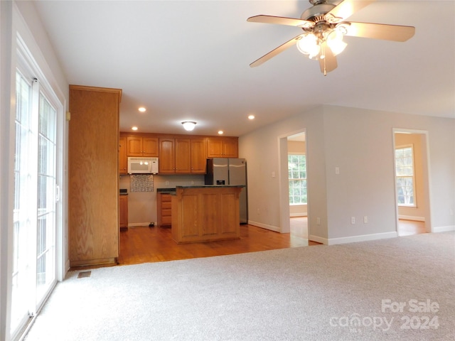 kitchen with open floor plan, light carpet, stainless steel fridge with ice dispenser, and white microwave