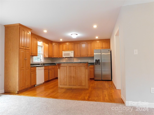 kitchen featuring a kitchen island, dark countertops, white appliances, and recessed lighting