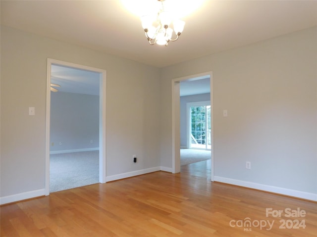 spare room with wood-type flooring and an inviting chandelier