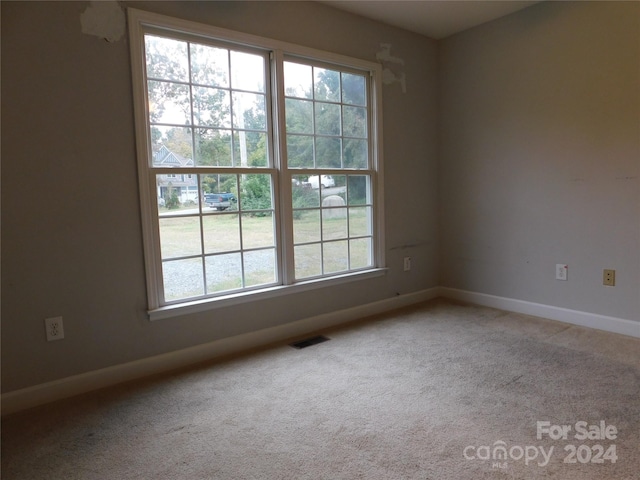 spare room featuring carpet floors, visible vents, and baseboards