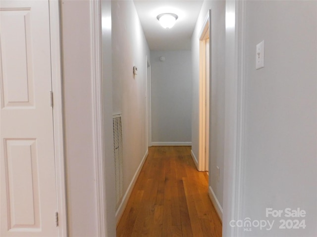 hall featuring light wood-style flooring and baseboards