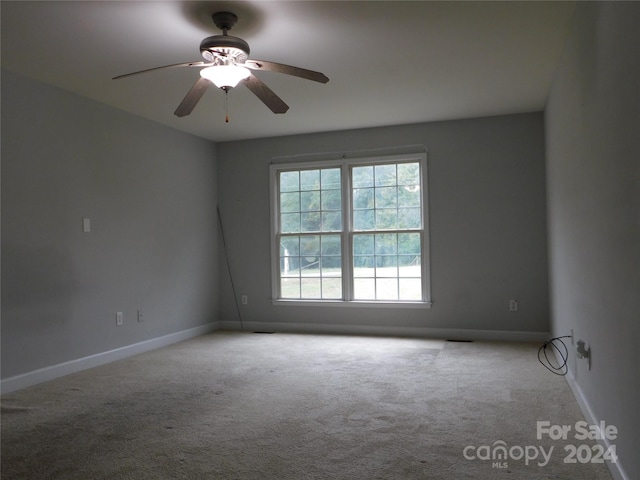 carpeted empty room featuring baseboards and ceiling fan