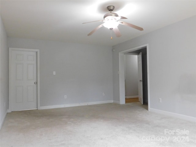 empty room featuring light carpet, baseboards, and ceiling fan