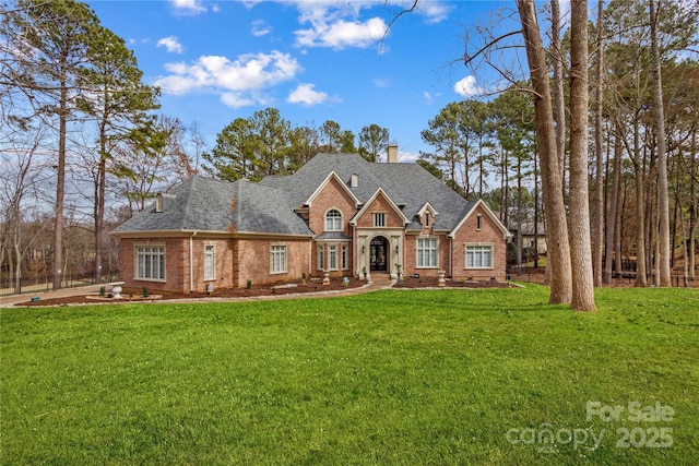 view of front of home with a front lawn, a chimney, brick siding, and crawl space