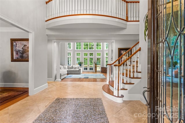 foyer entrance featuring stairway, a high ceiling, baseboards, and ornamental molding