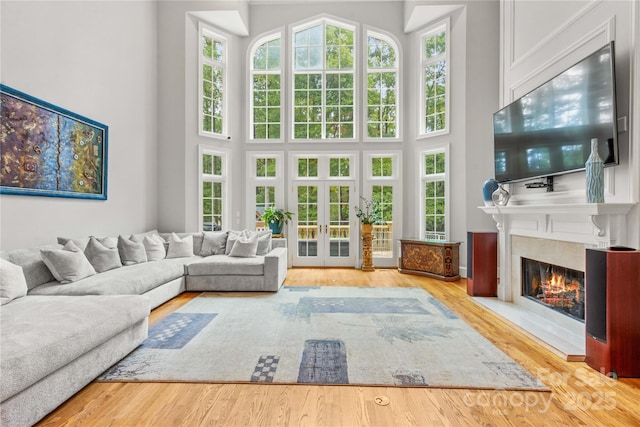 living area with a premium fireplace, french doors, a high ceiling, and wood finished floors