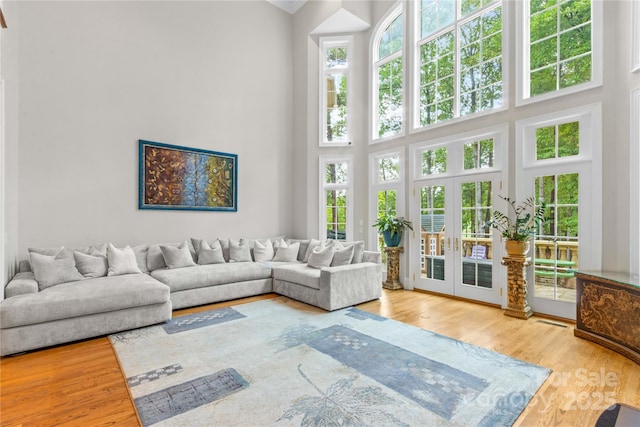 living area with a healthy amount of sunlight, french doors, a high ceiling, and wood finished floors