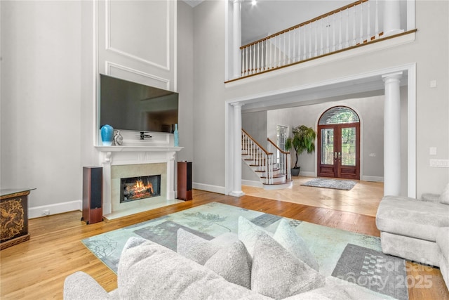 entryway with a high ceiling, a lit fireplace, wood finished floors, and stairs