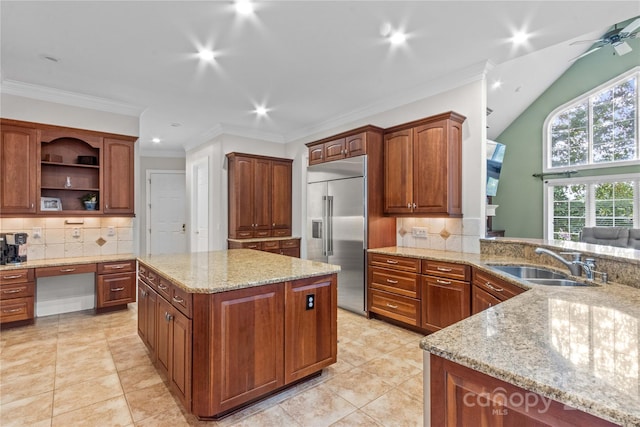 kitchen with light stone counters, built in study area, a sink, ornamental molding, and stainless steel built in refrigerator