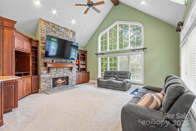 living room with beamed ceiling, light colored carpet, a stone fireplace, high vaulted ceiling, and a ceiling fan