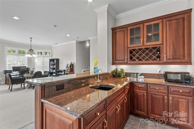 kitchen featuring a peninsula, crown molding, black microwave, and a sink