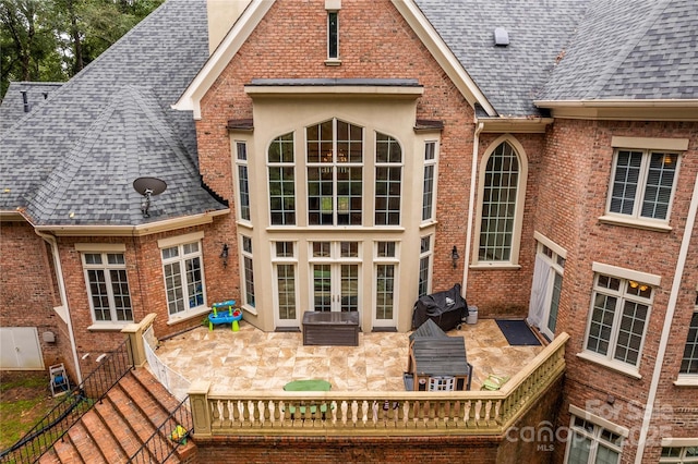 rear view of property with french doors, brick siding, and roof with shingles