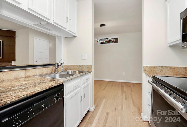 kitchen with appliances with stainless steel finishes, white cabinetry, light stone counters, light hardwood / wood-style flooring, and sink