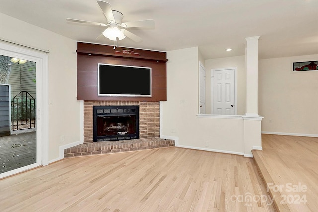 unfurnished living room with ceiling fan, a brick fireplace, and light hardwood / wood-style floors