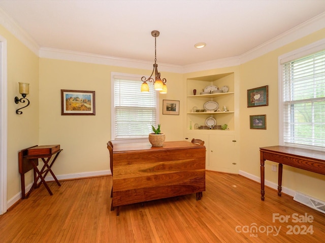 dining room featuring light wood-type flooring, built in features, ornamental molding, and a notable chandelier