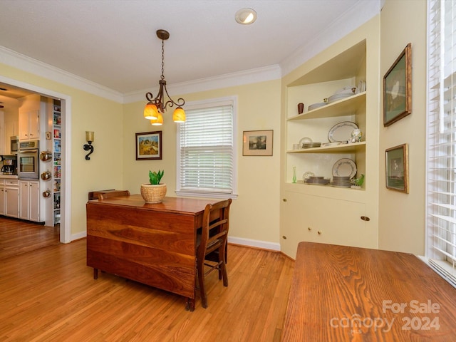 dining room with built in shelves, light hardwood / wood-style floors, crown molding, and an inviting chandelier