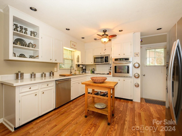 kitchen with white cabinets, sink, stainless steel appliances, and light hardwood / wood-style flooring