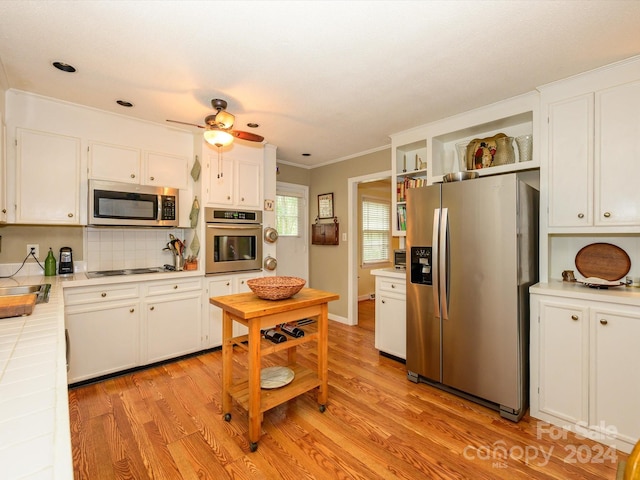 kitchen featuring tile countertops, light wood-type flooring, stainless steel appliances, and white cabinetry