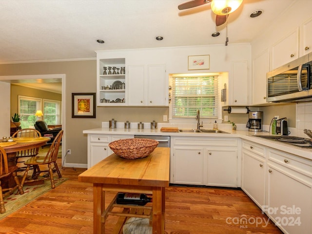 kitchen featuring appliances with stainless steel finishes, crown molding, sink, light hardwood / wood-style flooring, and white cabinets