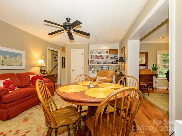 dining area featuring ceiling fan, light hardwood / wood-style flooring, built in features, and ornamental molding