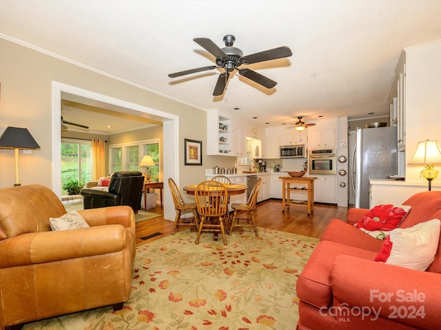 living room with ceiling fan, crown molding, and light hardwood / wood-style flooring