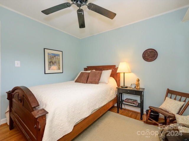 bedroom with hardwood / wood-style floors, ceiling fan, and crown molding