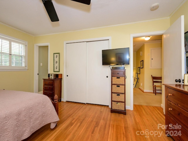 bedroom featuring ceiling fan, light hardwood / wood-style floors, crown molding, and a closet