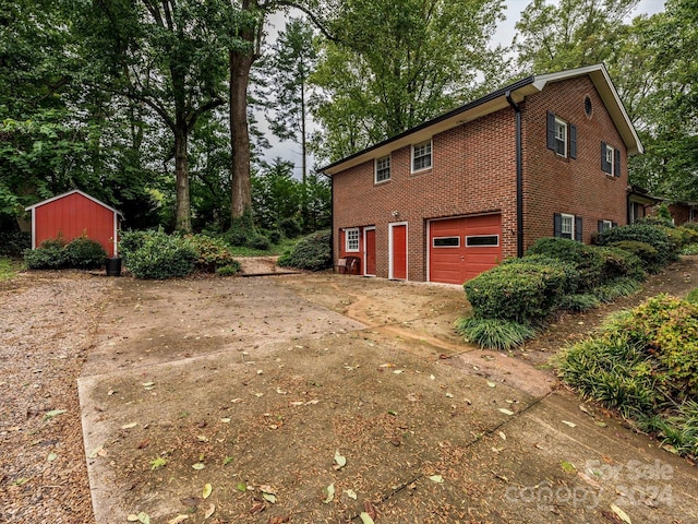 view of side of home with a storage shed and a garage