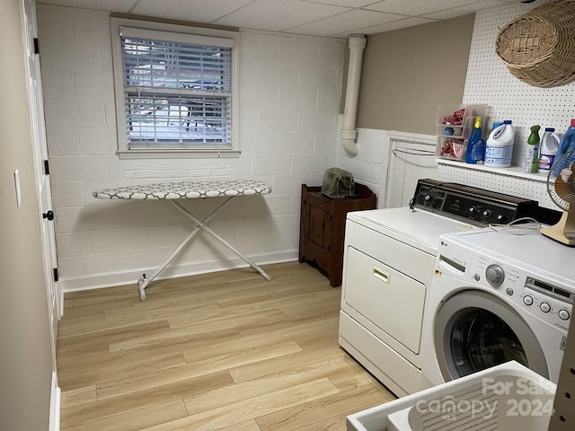 clothes washing area with washer and dryer and light wood-type flooring