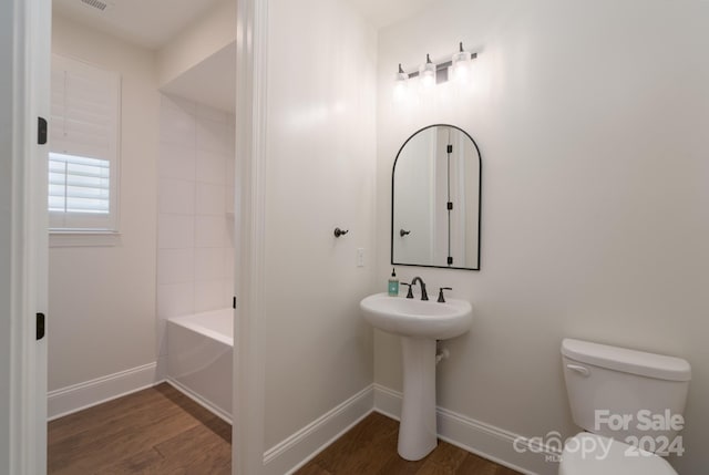 full bathroom with wood-type flooring, tiled shower / bath combo, sink, and toilet