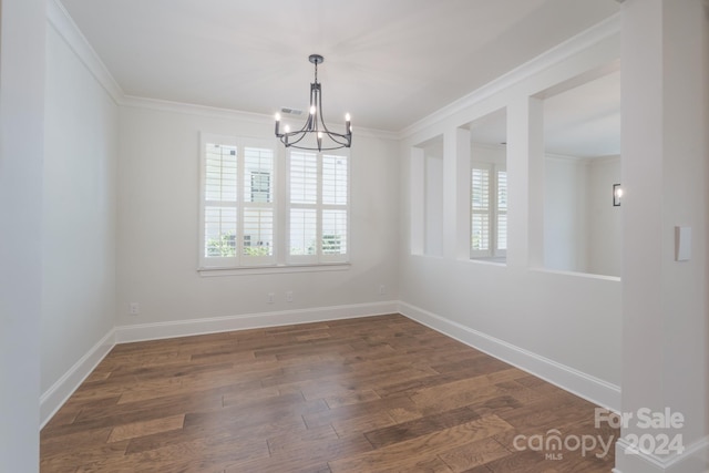 empty room with ornamental molding, dark hardwood / wood-style flooring, and a chandelier