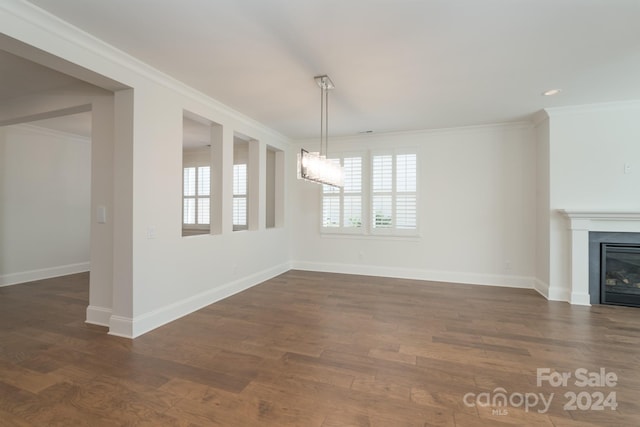 unfurnished living room with crown molding, dark wood-type flooring, and a chandelier