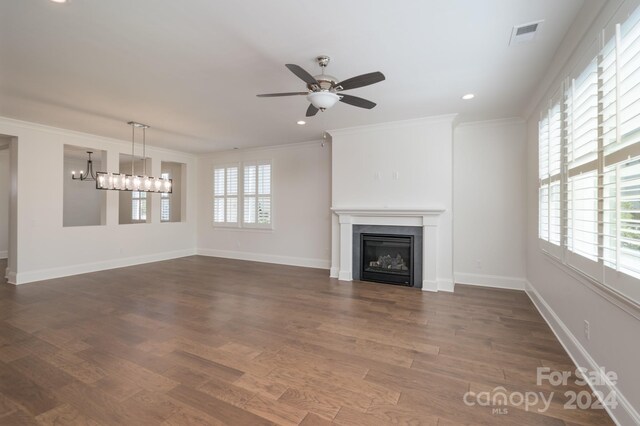 unfurnished living room featuring ceiling fan with notable chandelier, ornamental molding, dark hardwood / wood-style floors, and a wealth of natural light