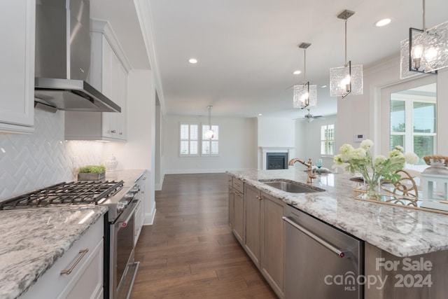 kitchen with appliances with stainless steel finishes, white cabinetry, wall chimney exhaust hood, dark hardwood / wood-style floors, and sink