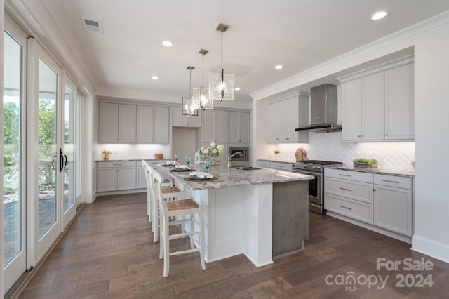 kitchen with high end stainless steel range, a center island with sink, wall chimney exhaust hood, and a wealth of natural light