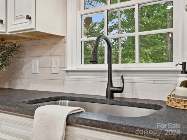 room details with backsplash, sink, and white cabinetry