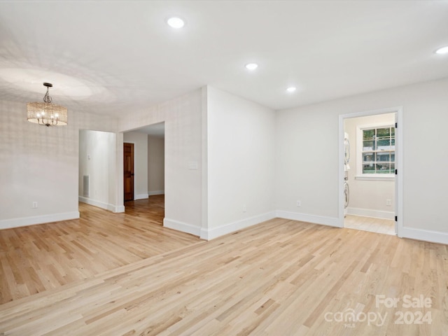 unfurnished room with light wood-type flooring and a chandelier