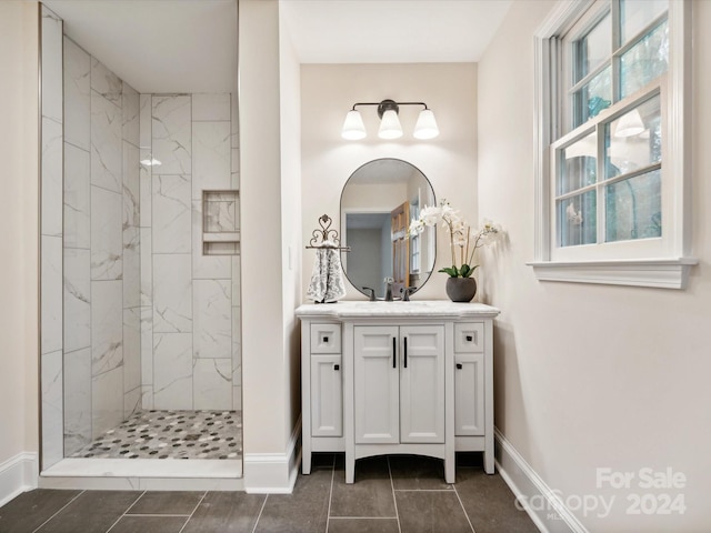 bathroom featuring a tile shower, vanity, and tile patterned floors