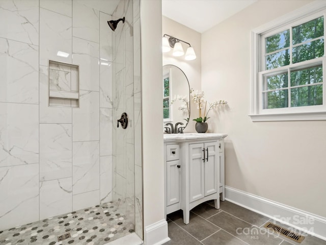 bathroom with tiled shower, vanity, and tile patterned flooring