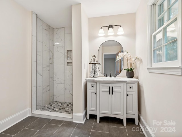 bathroom with tiled shower, vanity, and tile patterned floors