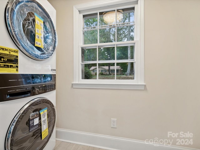 clothes washing area with stacked washing maching and dryer