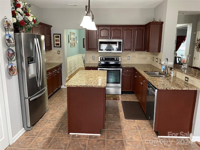 kitchen featuring hanging light fixtures, sink, tasteful backsplash, stainless steel appliances, and a center island