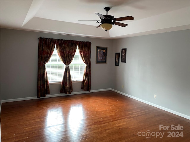 unfurnished room featuring ceiling fan, a raised ceiling, and hardwood / wood-style floors